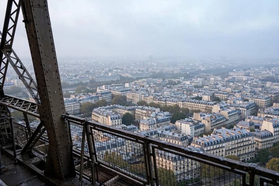 Eiffel Tower summit view over Paris rooftops morning