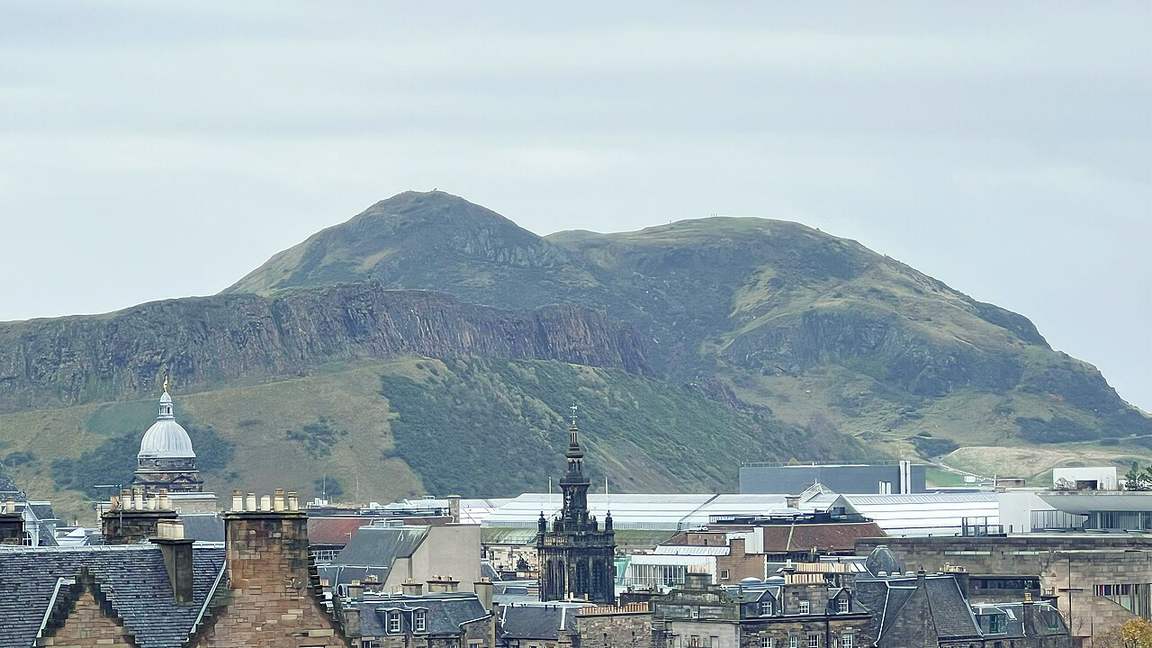 Arthur's Seat, the grassy remains of an extinct volcano, rising behind the rooftops of Edinburgh, Scotland