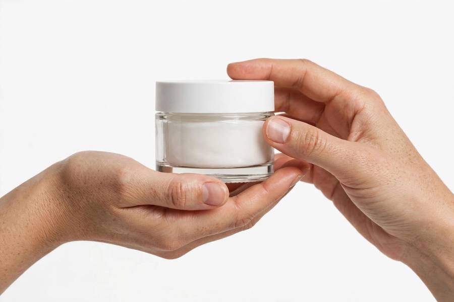 Hands holding an affordable moisturizer jar with simple packaging on white background, minimal beauty photography, photorealistic