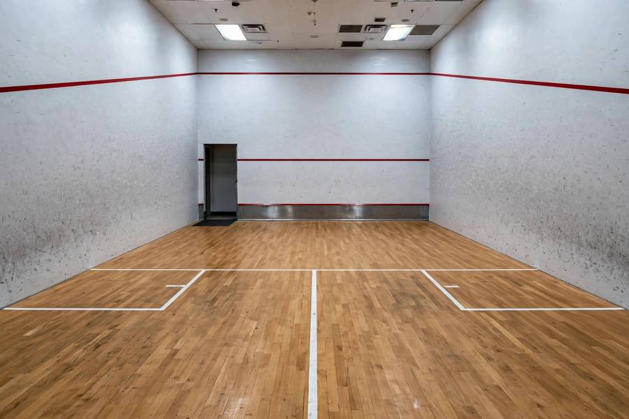 Photorealistic wide shot of an empty squash court showing the tin, service boxes and wall lines clearly