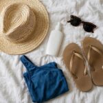 A flat-lay of beach vacation packing list essentials — hat, sunscreen, and light clothing