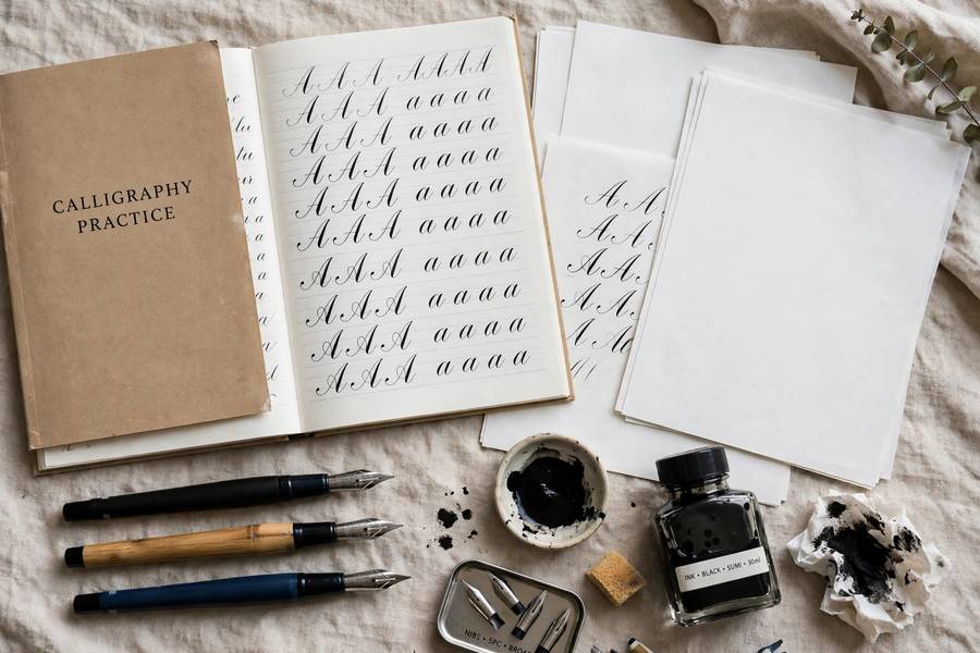 Calligraphy practice setup with pens and workbook