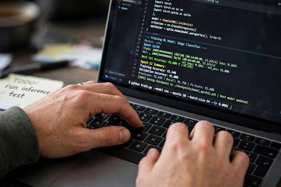 Hands typing code to train a machine learning model with accuracy metrics displayed