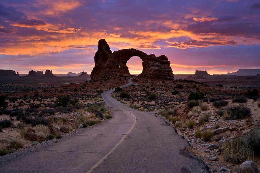 Desert national park road trip at sunset with sandstone arch
