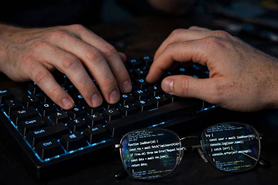A programmer typing code on a backlit keyboard