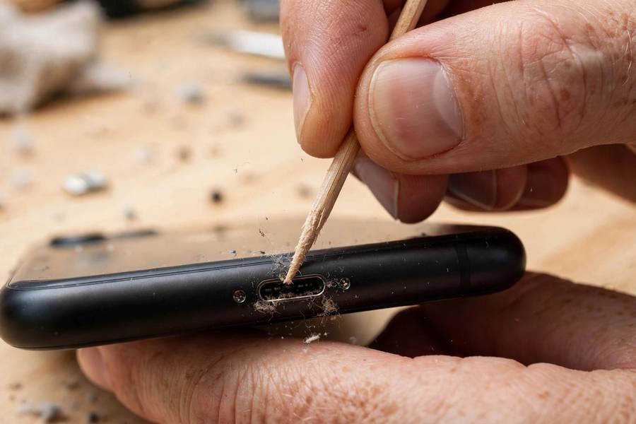 Gently cleaning an iPhone charging port with a wooden toothpick