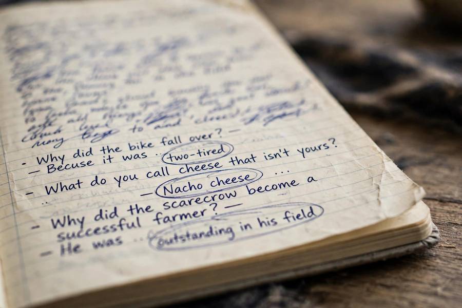 Close-up of handwritten joke list with punchlines circled in notebook