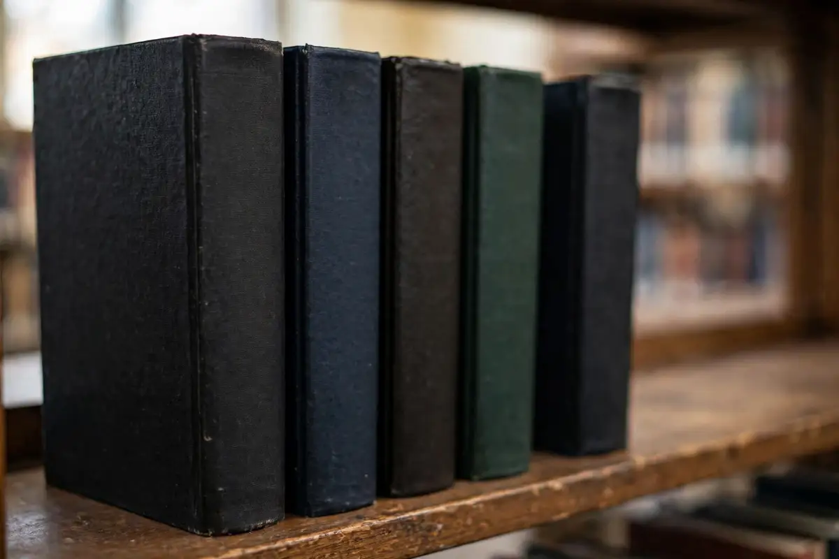 Hardbound doctoral dissertations standing on a university library shelf