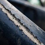 Close-up of a deep car scratch showing primer through the paint — do car scratches rust