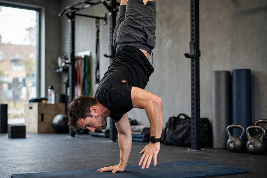Man practicing handstand balance drills on a mat