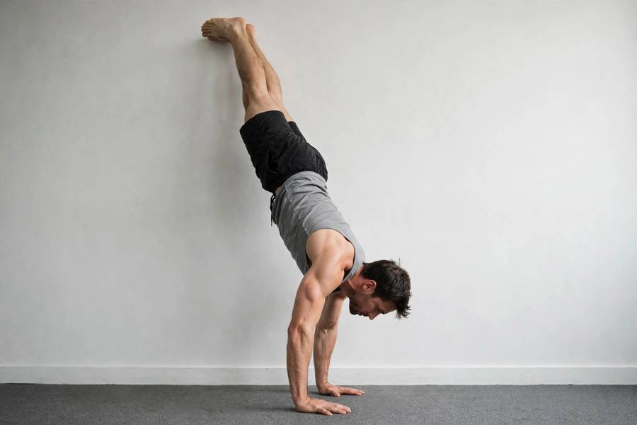 Person doing handstand shoulder shrugs against a wall