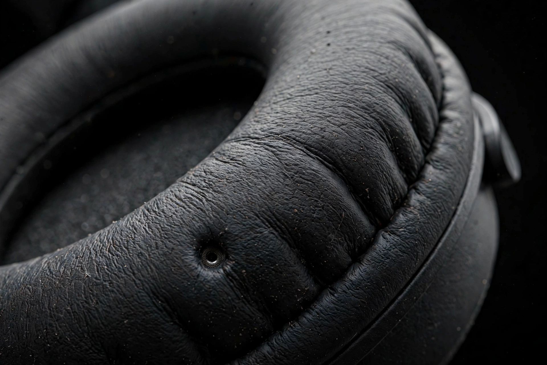 Macro of a headphone ear cushion with tiny microphone port — noise cancelling headphone microphone detail