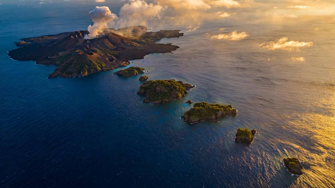 Aerial view of a volcanic island chain with one smoking island