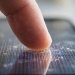 Fingertip touching a smartphone screen showing how a touchscreen works at the glass level