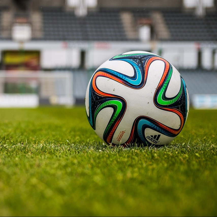 A soccer ball resting on fresh green pitch grass