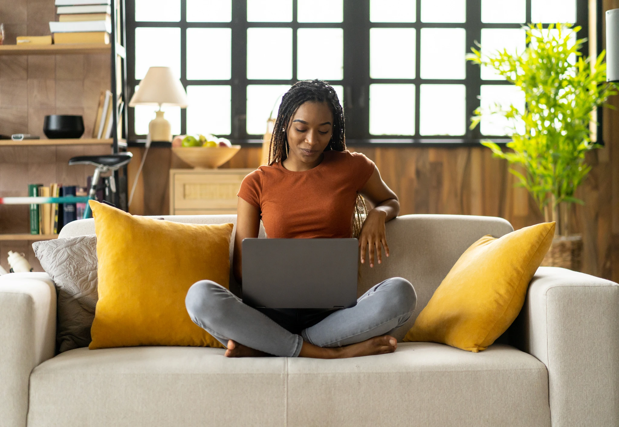 A person browsing on a laptop while sitting on a couch in a cozy living room