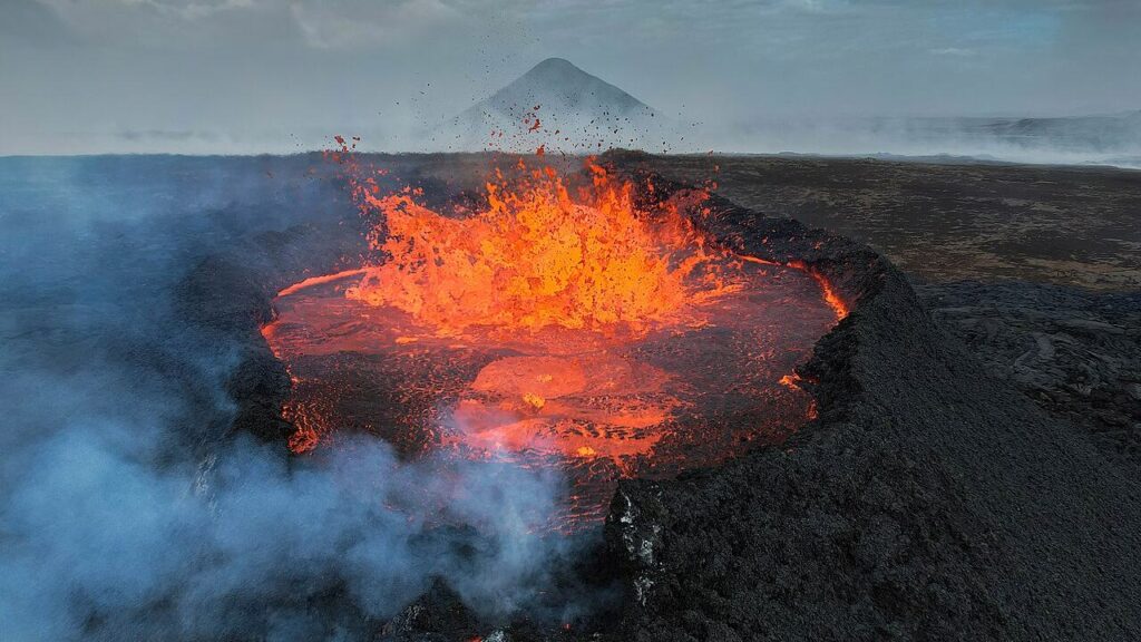 Bright orange lava erupting and splashing in a lava lake inside a volcanic crater