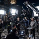 How Long Does It Take to Film a Movie? Timelines Explained A film set at night with a camera crane and crew