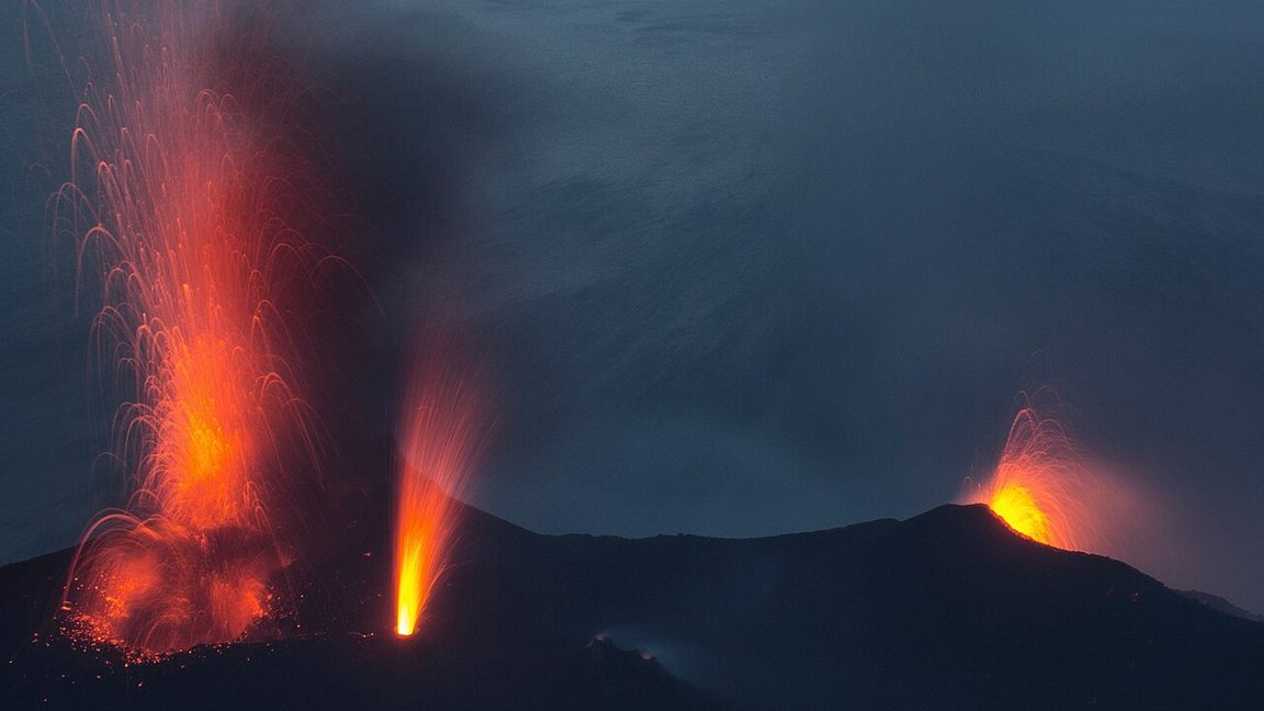 Stromboli volcano in Italy erupting from three vents at dusk, as it does almost constantly