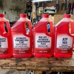 How Much Transmission Fluid Do I Need? Capacities by Service Type Quart bottles of red automatic transmission fluid lined up on a workbench