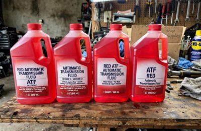 Quart bottles of red automatic transmission fluid lined up on a workbench