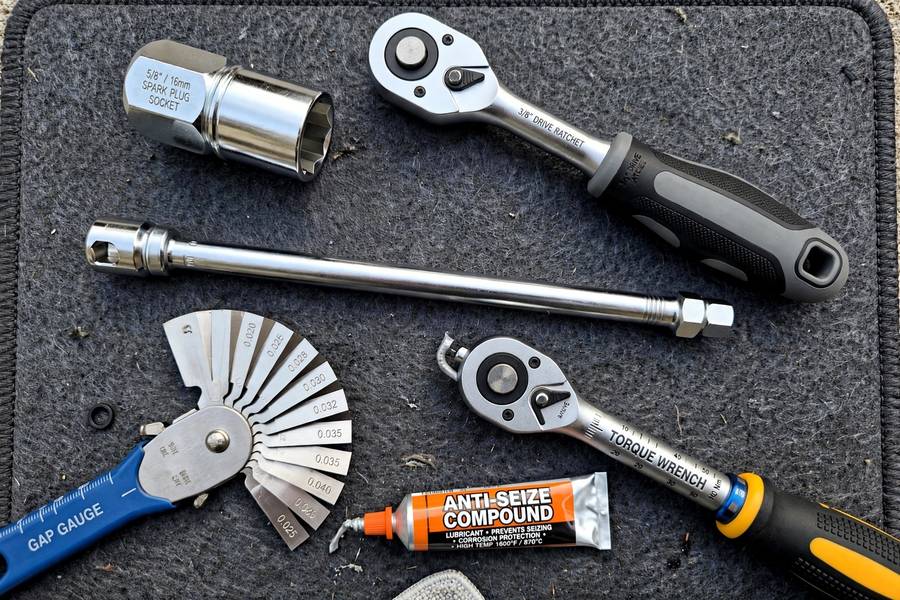 Tools laid out for how to change spark plugs: socket, gap gauge, and torque wrench