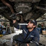 How to Check Transmission Fluid Without a Dipstick: Sealed Transmissions Explained Mechanic under a lifted car locating the transmission fluid fill plug