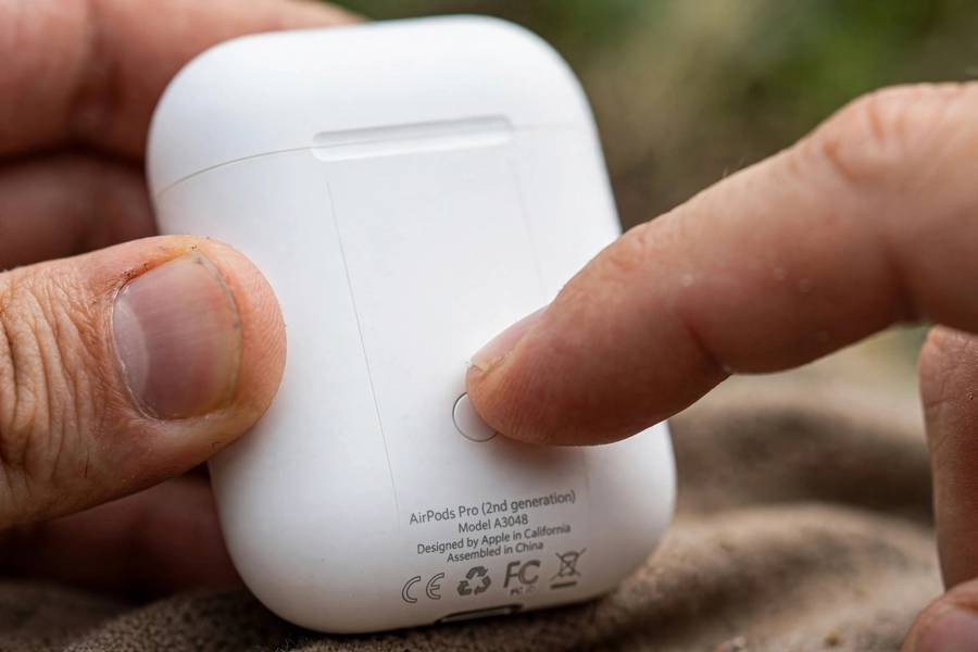 Pressing the setup button on the AirPods case to connect AirPods