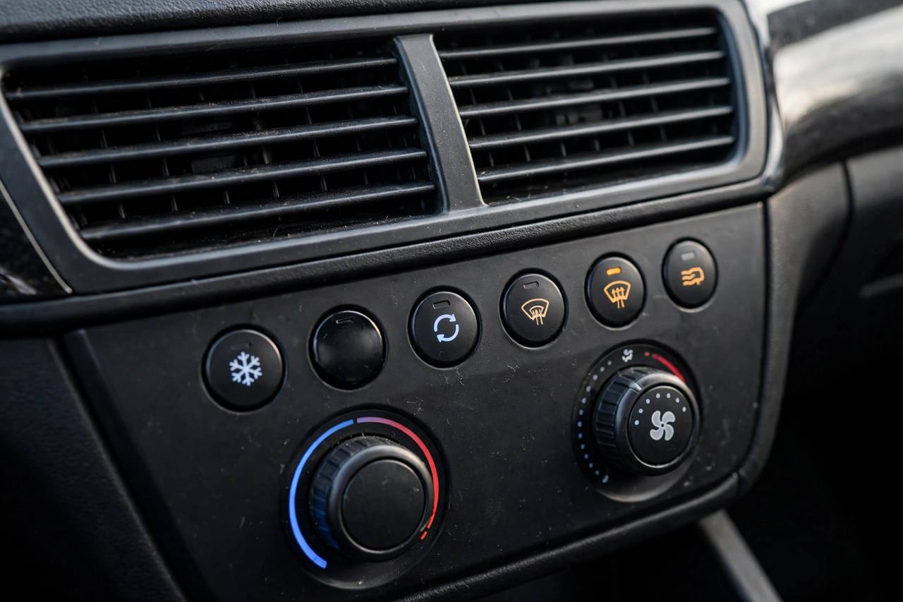 Car dashboard close-up showing defroster vents and climate controls with the AC button