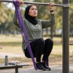 How to Do Your First Pull-Up: A 6-Week Beginner Plan Woman doing a band-assisted pull-up while working toward her first unassisted rep