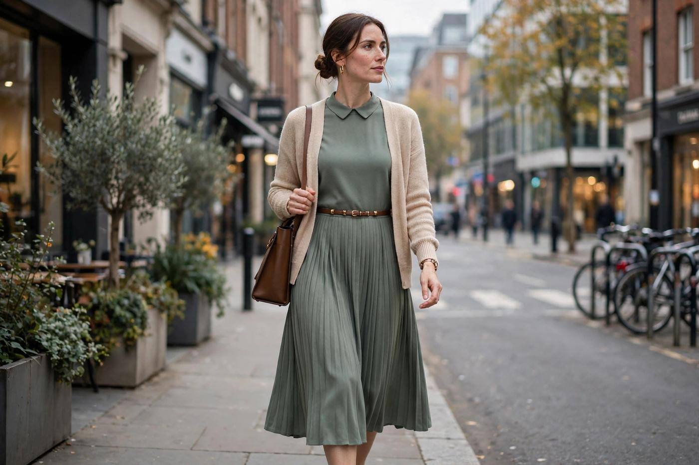 Elegant woman wearing a long-sleeve midi dress and cardigan walking through a city street to work