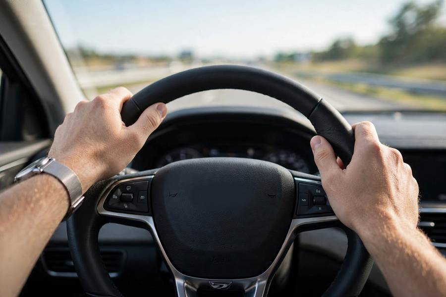 Driver's hands on the steering wheel during smooth highway driving