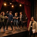 Students in an acting class performing an exercise on stage