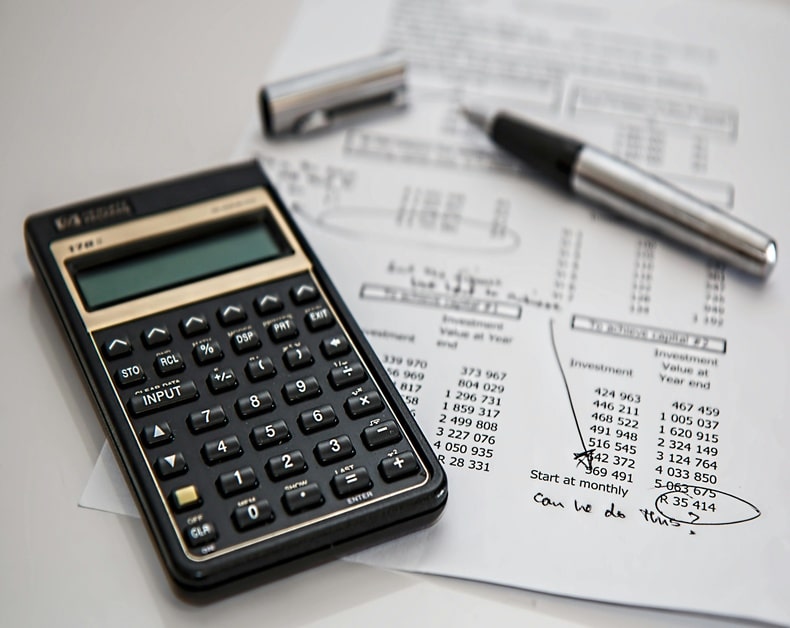 Calculator next to financial documents and a pen on a desk