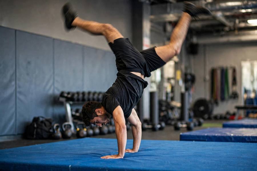 Person mid-kick-up into a handstand on a gym mat