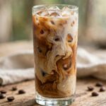 How to Make Iced Coffee at Home (Better Than the Café) Tall glass of homemade iced coffee with milk swirl and ice cubes