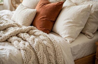 A cozy bedroom with warm lamplight and layered bedding