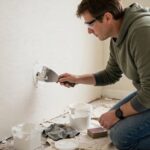 How to Patch a Hole in Drywall: From Nail Holes to Big Gaps Person applying spackle to a small drywall hole with a putty knife