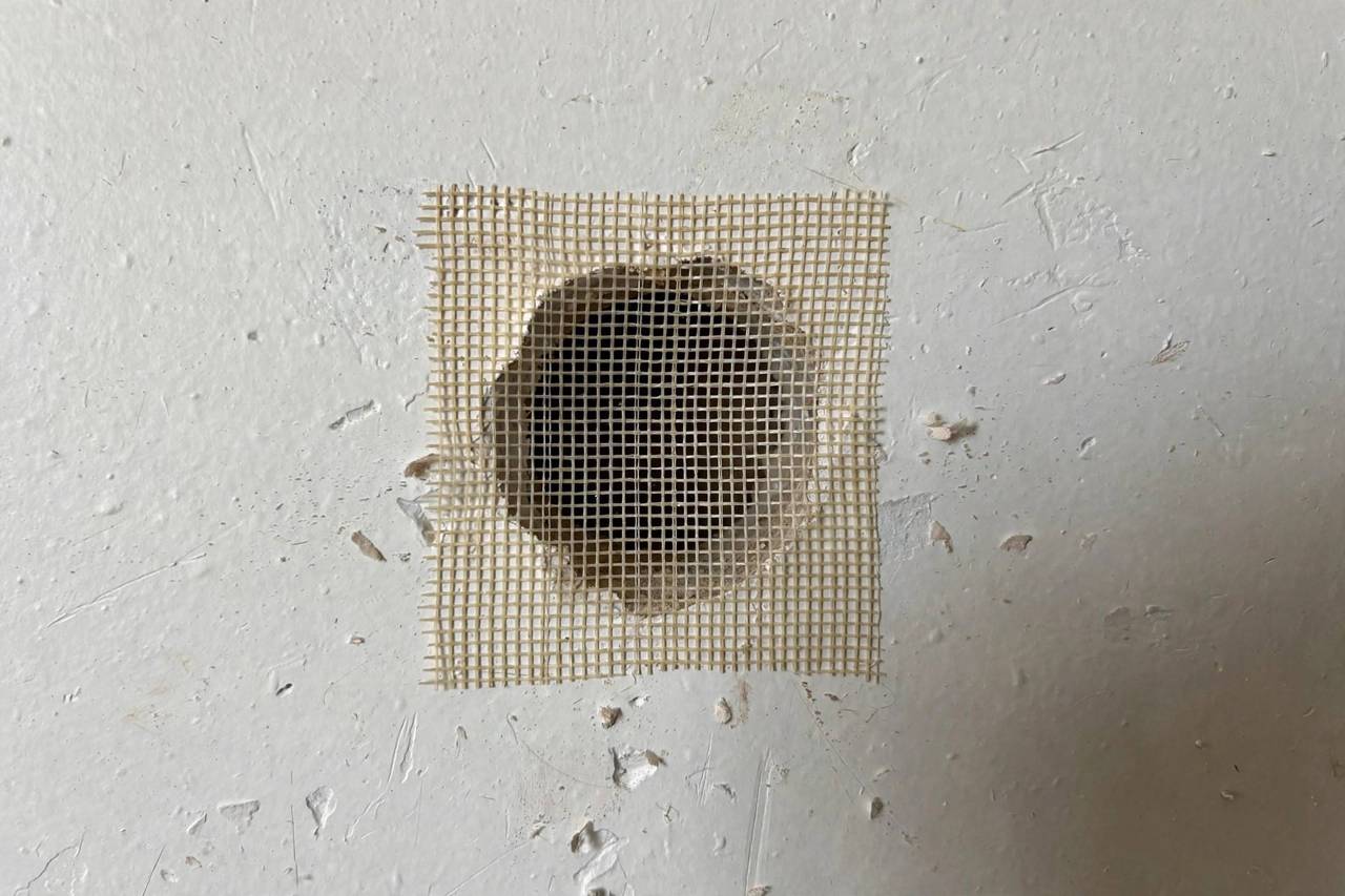 Person applying spackle to a small drywall hole with a putty knife