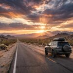 How to Plan a Road Trip Itinerary: The Anchor-First Method A car driving on a scenic open highway through desert landscape at sunrise