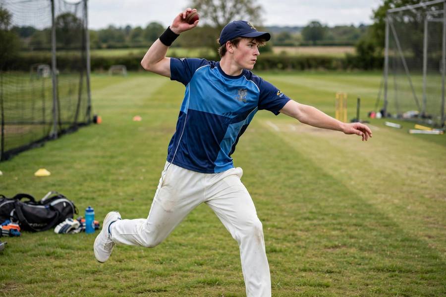 Young player practicing cricket bowling on a grass field
