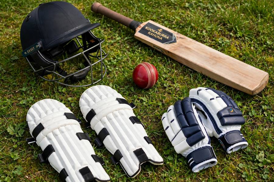 Cricket equipment laid out: bat, ball, pads, gloves and helmet