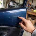 How to Remove Scratches From Car Paint: A Mechanic's DIY Guide Inspecting a light scratch on a car door in a home garage