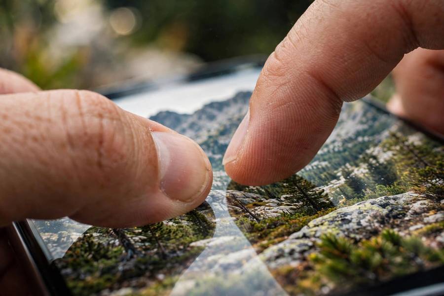 Close-up of fingers zooming into photo details on a smartphone screen during verification