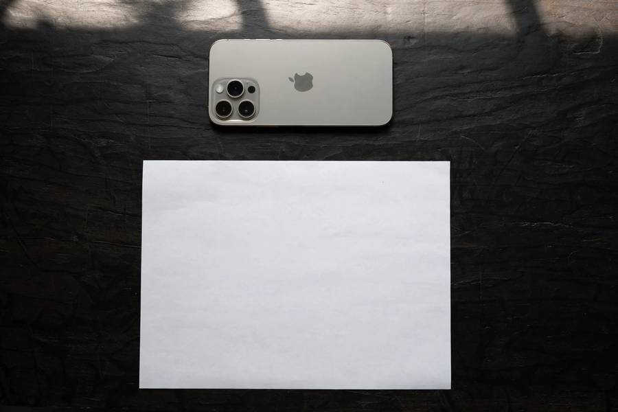 Overhead view of iPhone positioned above a document on a dark table for scanning