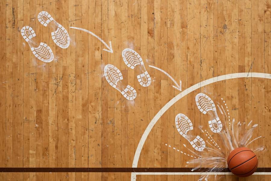 Photorealistic image showing layup footwork steps diagram-style on a basketball court floor