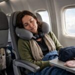 How to Sleep on a Plane Comfortably: The Complete Playbook Woman sleeping peacefully on an airplane with travel accessories