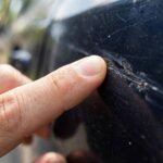 Hand doing the fingernail test to tell if a car scratch can be buffed out