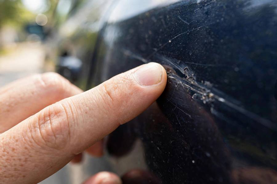 Hand doing the fingernail test to tell if a car scratch can be buffed out