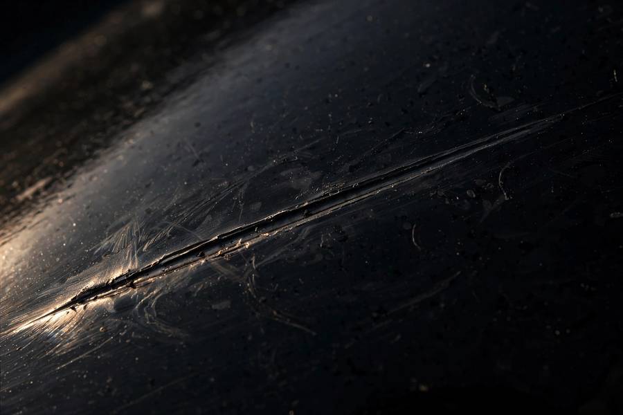 Close-up of a shallow car scratch in the clear coat that can be buffed out